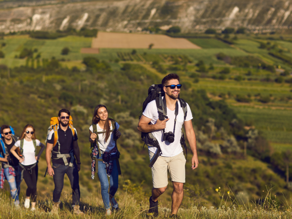 Happy people in a line hiking on a green mountain and how to decrease symptoms of stress by exercising.