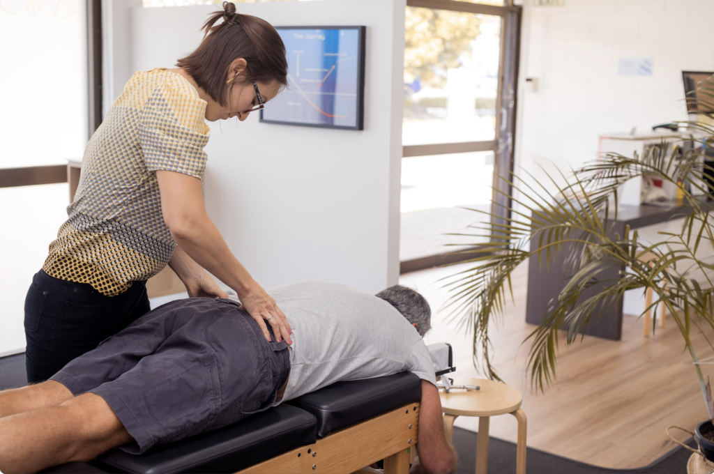 A female chiropractor adjusting an older man. Chiropractic can be a tremendous help in decreasing the pain caused from cervical facet syndrome, while also helping to correct the cause of this syndrome. 