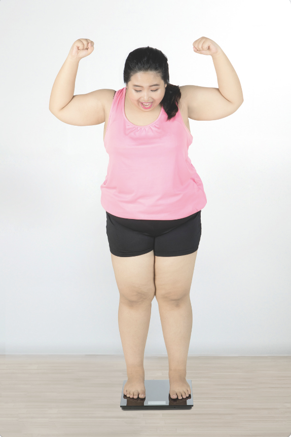 A young woman excited she is losing weight. Losing weight can help reduce the strain on the neck and decrease the pain from cervical facet syndrom.