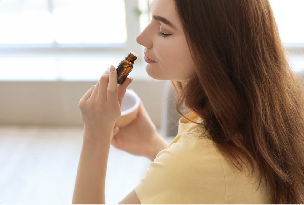 A young woman smelling an essential oil. Some essential oils can help you to open up and breathe easier when you are shut down from allergies.