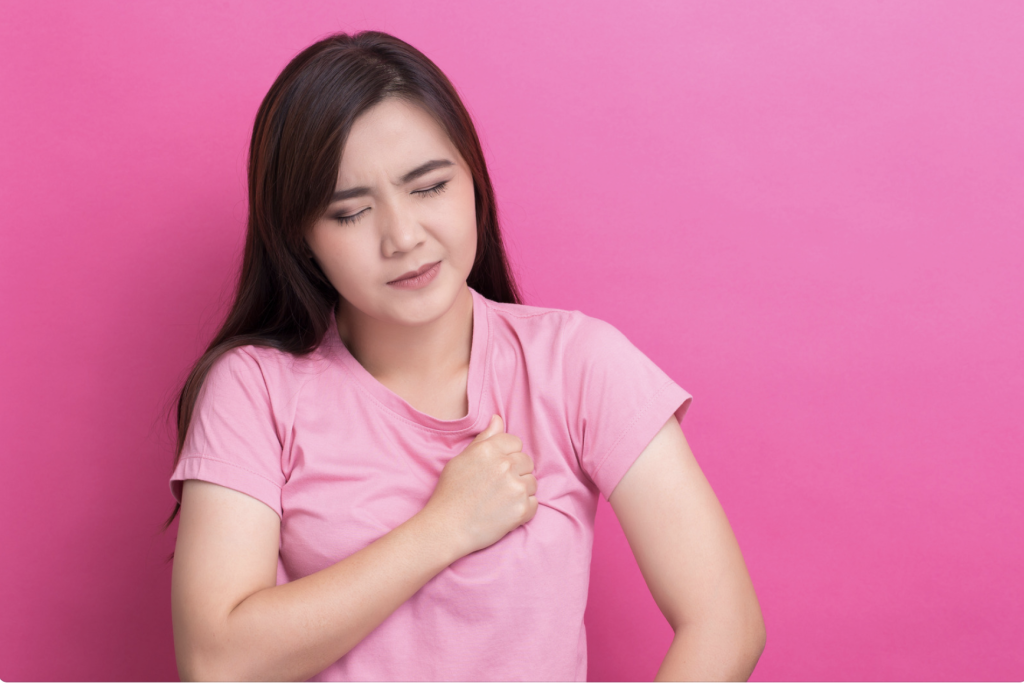 A young woman holding her chest because of pain. A lot of allergies will irritate the ribs and surrounding tissues and can cause chest pains.