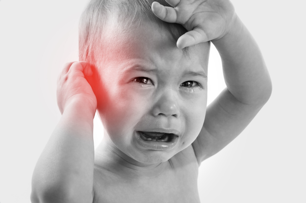 A young baby holding his ear because of pain. Allergies are a large cause of ear infections in children.