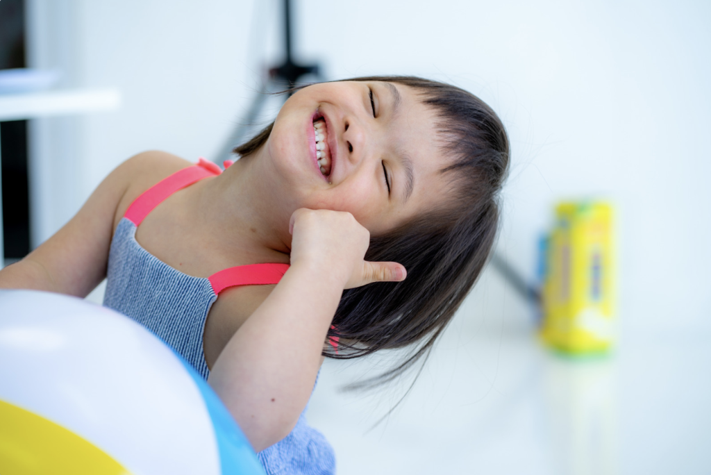 Beautiful little girl with autism smiling as she is playing with a beach ball.