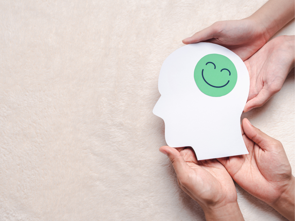 Picture of 2 people holding a picture of a head with a smily face in the brain and how to decrease symptoms of stress by addressing mental health concerns.