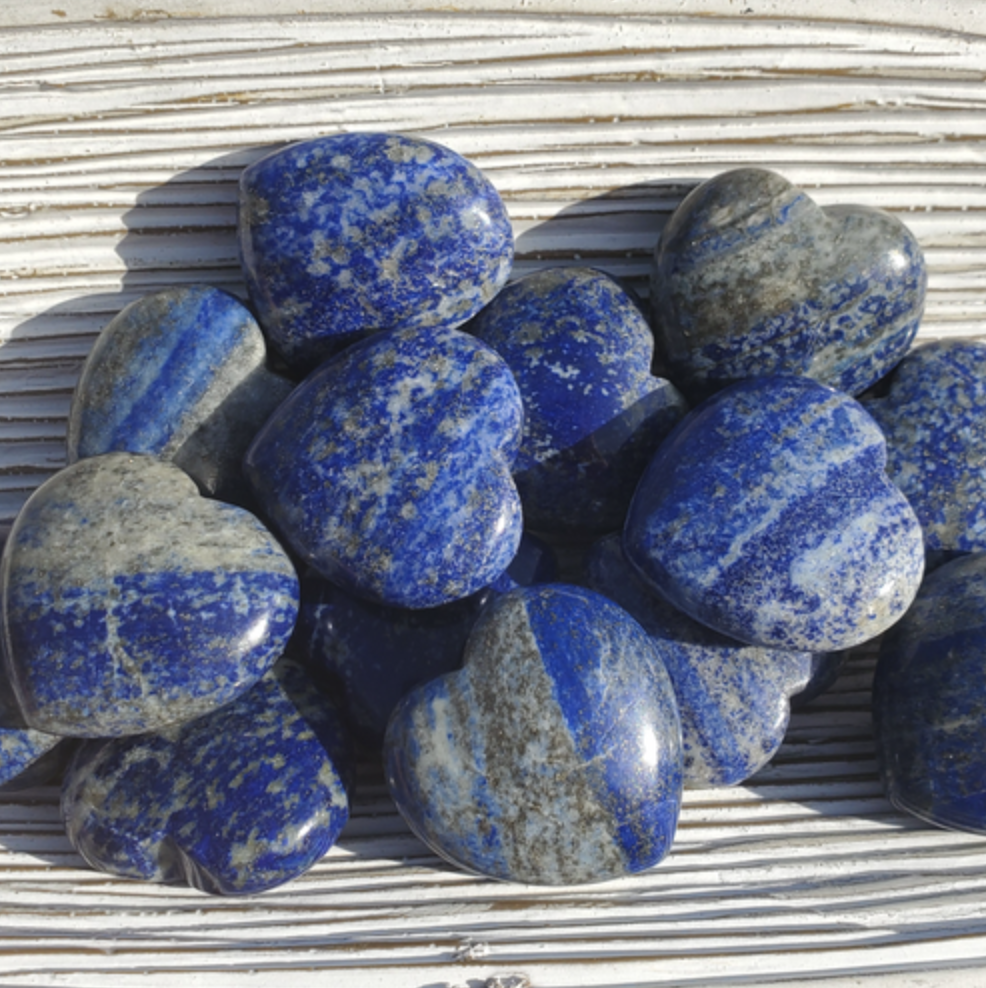 Multiple blue colored lapis lazule stones on a white surface. 